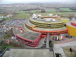 Luftbild der Gebäude, mit dem rot-gelben Rundgebäude in der Mitte 